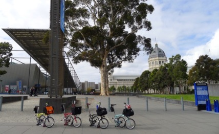 Bromptons in a line before the Melbourne Museum (left) and Royal Exhibition Building (right)